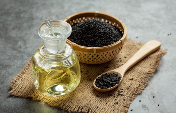 زجاجة صغيرة تحتوي سائل أصفر اللون وبجانبها وعاء يحتوي بذور سوداء اللون