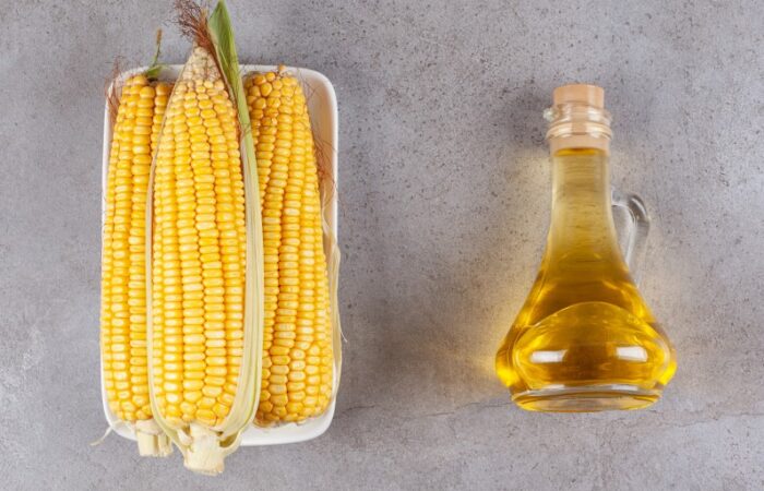 ذرة صفراء وبجانبها زجاجة بداخلها سائل أصفر اللون