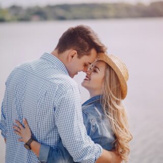 رجل وامرأة متعانقان ينظران لبعض أمام ضفة البحيرة