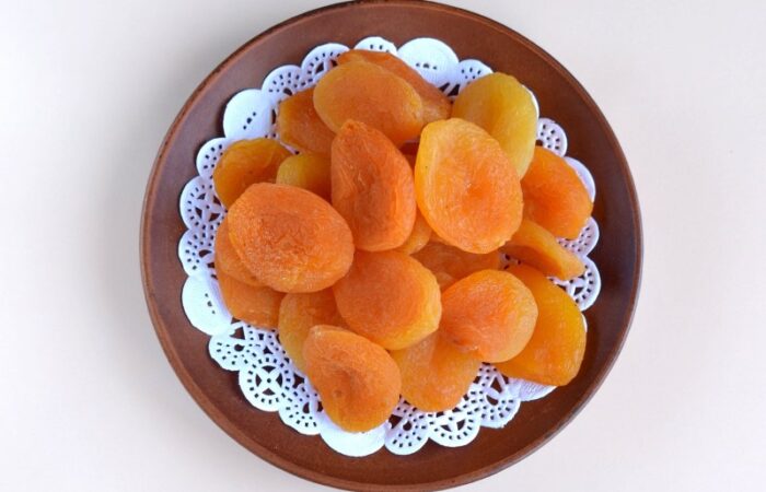 صحن بني اللون وبداخله حبات من المشمش المجفف