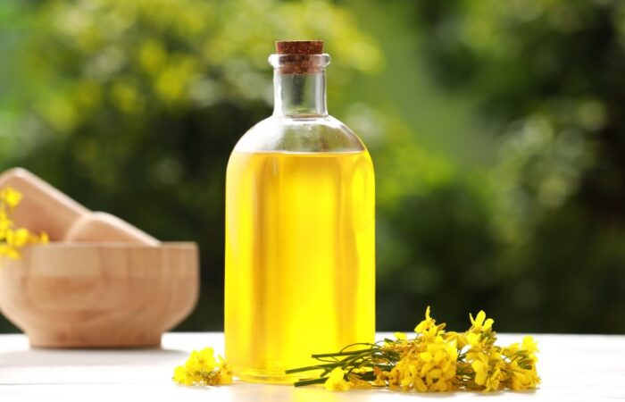 زجاجة تحتوي على سائل أصفر اللون بجانبها زهور صفراء اللون على طاولة خشبية