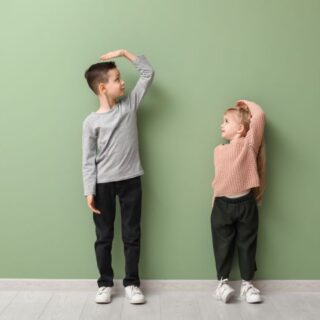 صبي وفتاة يضعون أيديهم فوق رؤوسهم وخلفهم جدار أخضر اللون