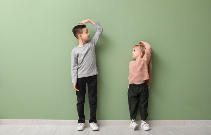 صبي وفتاة يضعون أيديهم فوق رؤوسهم وخلفهم جدار أخضر اللون