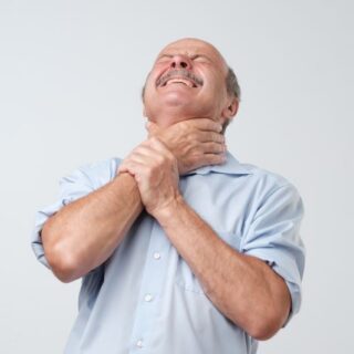 رجل مسن يرتدي قميص أزرق رافعاً رأسه للأعلى ويضع يد حول عنقه