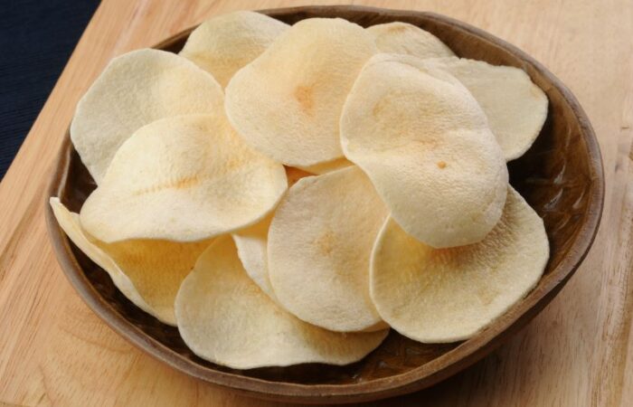 شرائح دائرية الشكل من البطاطا في صحن بنّي موجود على طاولة