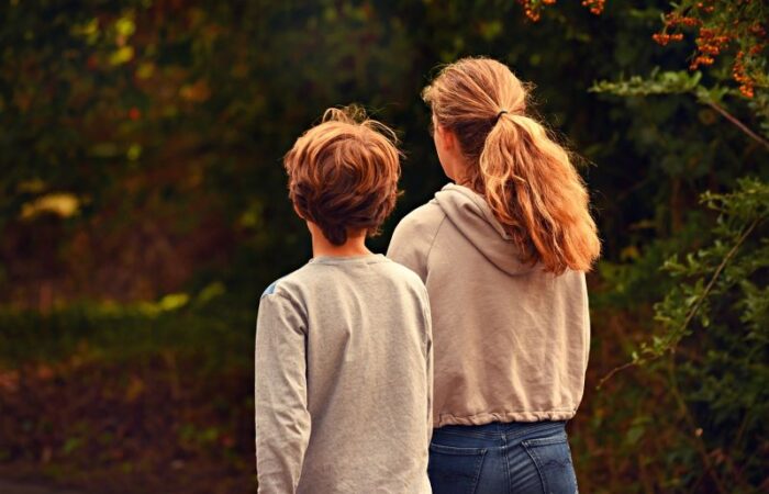 بنت وصبي يمسكان بيد بعض ويتنزهان في الغابة