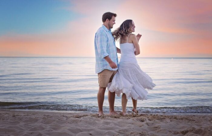 رجل يراقص امرأة على شاطئ البحر عند المغيب