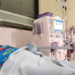 امرأة آسيوية مسنة ممددة على السرير في المستشفى وبجانبها جهاز غسيل الكلية