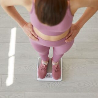 امرأة بالغة تضع يديها على خصرها وهي تقف على ميزان الوزن