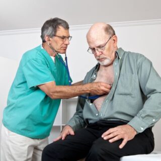 طبيب يضع سماعة جهاز قياس دقات القلب على صدر رجل مسن