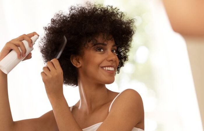 امرأة شابة سمراء البشرة مبتسمة تسرح شعرها المجعد