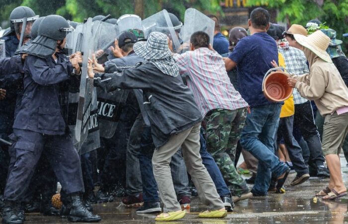 مجموعة من رجال الشرطة تمسك دروع بيدها بوجه مجموعة من الشباب