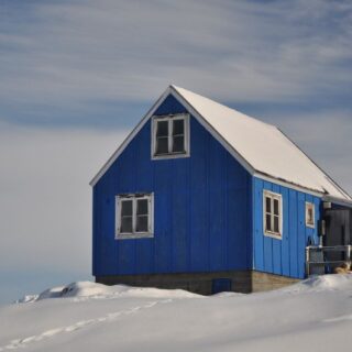 منزل خشبي أزرق اللون وحوله الثلج الأبيض