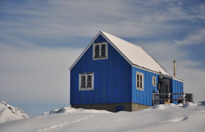 منزل خشبي أزرق اللون وحوله الثلج الأبيض