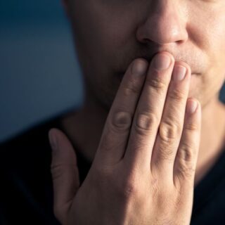 رجل بالغ يضع أصابع يده على فمه