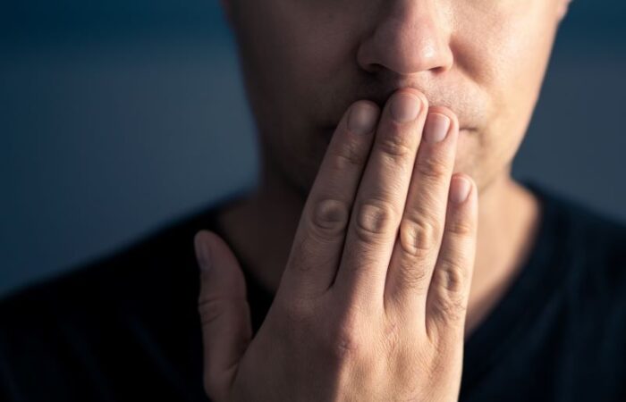 رجل بالغ يضع أصابع يده على فمه