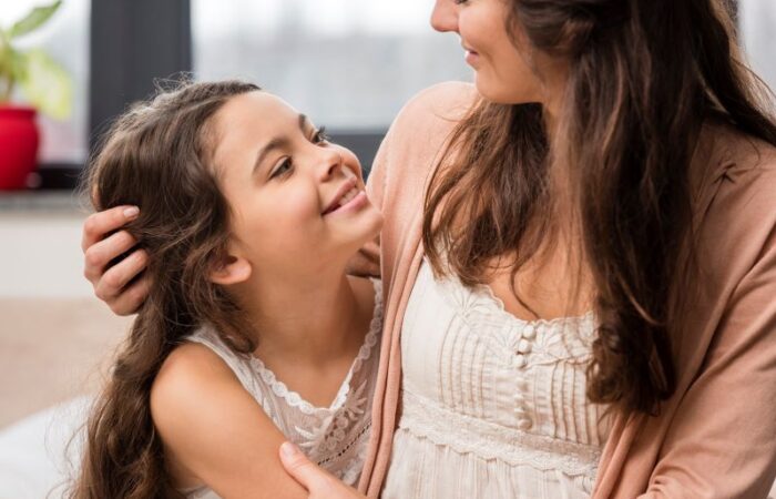 امرأة ناضجة تعانق ابنتها وتنظر لوجهها وهي مبتسمة