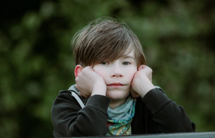 طفل حزين يضع يديه على خديه