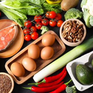 مجموعة من المأكولات: البيض، شرائح السمك، البروكلي، قرنبيط، الطماطم، فلفل حار، الأفوكادو، الجوز، اللوز، وأوراق الخس