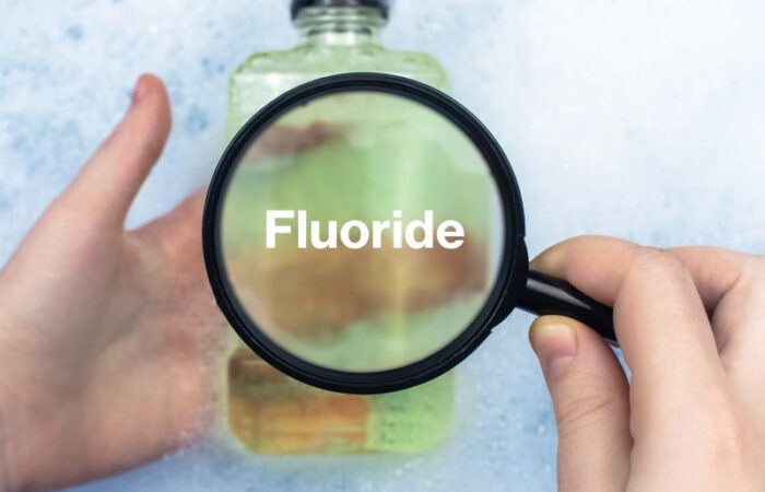 شخص يمسك بيديه علبة بلاستيكية مكتوب عليها بالإنكليزية Fluoride