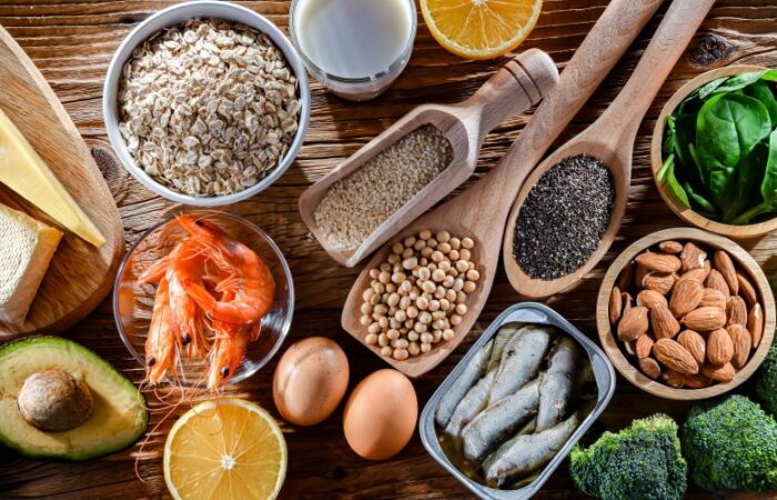 مجموعة من الأطعمة: القريدس، السمك، البيض، الأفوكادو، بذور السمسم، اللوز، الحمص، الشوفان، والورقيات كالسبانخ